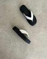 Ojotas negras con base cuadrada y tiras blancas.