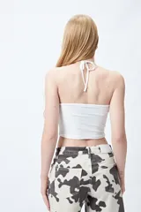 Top halter corto negro con tiras finas para anudar en la nuca.