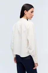 Camisa blanca con rayas verticales, de manga larga y cuello tipo mao, con botón frontal.