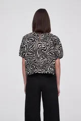 Blusa con estampado animal print en blanco y negro, de mangas cortas abullonadas y cuello redondo.