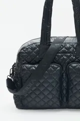 Bolso marrón con diseño matelassé, doble asa corta, correa larga desmontable y dos bolsillos frontales. Incluye llavero de corazón y dijes desmontables.