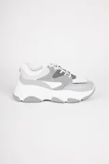 Zapatillas blancas con recortes en diferentes tonos de gris, cordones y plataforma irregular de 5cm.