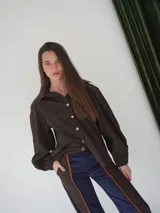 Camisa marrón con botones blancos, de corte clásico y mangas largas abullonadas.