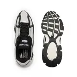 Championes urbanos Lacoste modelo L003 2K24, con capellada de malla gris y detalles en cuero sintético negro y plateado. Suela chunky blanca con detalles en negro. Logo de Lacoste en el lateral.