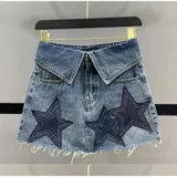 Minifalda de jean celeste con cintura alta estilo camisa y apliques de estrellas en azul marino con costuras blancas.