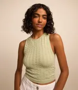 Blusa cropped sin mangas color verde claro, con escote halter y textura de punto abierto.