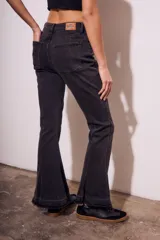 Pantalón de jean negro con corte flare, tiro medio y ruedo desflecado.