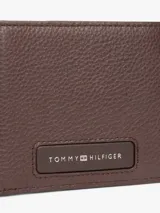 Billetera Tommy Hilfiger de cuero marrón con textura granulada. Diseño plegable con múltiples ranuras interiores para tarjetas y logo metalizado en la parte delantera.