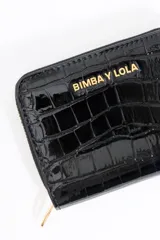 Cartera con solapa de acabado en color plateado, con grabado de cocodrilo, cierre de cremallera y tarjetero interior.
