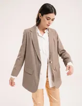 Blazer oversized de casimir 100% lana, de corte recto y largo a la cadera, con cierre delantero de dos botones y hombreras finitas.