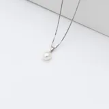 Conjunto de collar y aros de plata 925 con perlas de río blancas. El collar tiene una cadena de eslabones cuadrados y un dije con una perla. Los aros son colgantes con una perla cada uno.