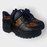Zapatillas negras con detalles en animal print naranja y cordones negros.