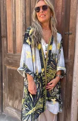 Kimono de seda con mangas anchas y estampado de motivos naturales en tonos negro, amarillo mostaza y gris claro. Presenta un ribete decorativo en el frente.