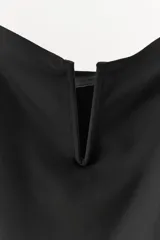 Vestido corto negro confeccionado en hilatura con poliamida. Presenta escote corazón con pieza metálica forrada en el pecho y tirantes finos ajustables.