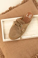 Mocasines tipo mule color beige, con detalle de cordones y ojales metálicos.