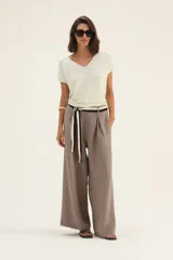 Pantalón ancho de lino color beige con cinto blanco y negro.