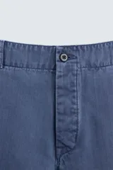 Pantalón azul de corte recto, con cintura ajustable, bolsillos laterales y traseros, y bolsillo tipo plastrón en la pierna. Tiene un lavado vintage con efecto de manchas.