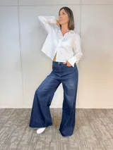 Camisa blanca de algodón con cuello clásico, corte recto y mangas largas con puños abotonados. Cierre frontal con botones.