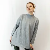 Sweater negro de tejido texturizado, con cuello alto, mangas 3/4 y corte asimétrico con aberturas laterales.