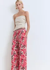 Pantalón de viscosa con estampado floral en tonos rojo, blanco y marrón. Tiene cintura elástica con cordón ajustable, corte recto y dos bolsillos laterales.