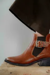 Botines Chelsea color beige con elásticos laterales negros, punta cuadrada, detalle de hebilla lateral y tacón bloque bajo.