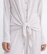 Conjunto de pijama largo en tejido de punto color gris claro. Incluye una remera de manga larga con cuello en V, botones frontales y lazo en la cintura, y un pantalón largo con cintura elástica y puños ajustados.