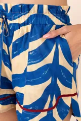 Short con estampado de ondas fluidas en azul y blanco, pretina elastizada con cordón y ruedo con ribete trenzado color bordó.