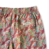 Short de baño blanco con estampado de hojas de palmera en tonos verde, rojo y amarillo.