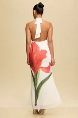 Vestido largo de fiesta color blanco con estampado de una flor roja. Tiene escote halter y espalda descubierta.