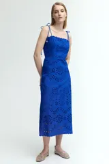 Vestido midi azul con breteles finos con moño y escote recto. Tiene broderie floral calado en todo el vestido y ribete festoneado en el escote y el ruedo.