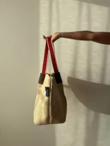 Bolso negro tipo tote de neopreno con bolsillo interno de red, sobre haciendo juego y gancho para sujetarlo.