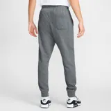 Pantalón de jogging gris oscuro con logo de Nike bordado en blanco. Tiene cintura elástica con cordón ajustable y puños ajustados.