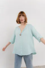 Blusa verde salvia de lino, con escote en V, manga corta y un botón de madera al frente.