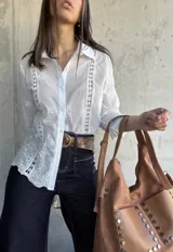 Camisa blanca de manga larga con bordado inglés y cierre frontal con botones.