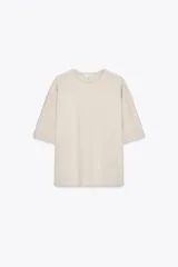 Camiseta color beige de corte amplio, cuello redondo y mangas cortas.