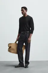 Jersey negro de lana con acabado mercerizado, corte relaxed fit, cuello redondo y mangas largas con terminaciones en rib.