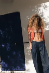 Chaqueta de punto color naranja con cuello redondo y manga corta. Presenta cierre frontal con botones y estampado de rombos en tonos blanco, naranja y marrón.