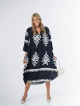 Vestido midi oversized con estampado en fondo negro, cuello tipo camisa, escote en V y tajos laterales.