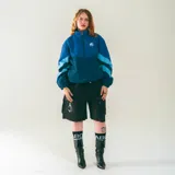 Campera deportiva azul confeccionada en nylon liviano, con paneles diagonales en contraste y micrográfico Kaboa aplicados al frente y un gráfico en la espalda.