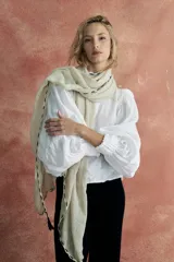 Pashmina color crudo con detalle de pespuntes negros en los bordes y borlas en las puntas.