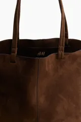 Cartera tipo tote bag color marrón, con asas finas y costuras decorativas.