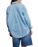 Camisa a rayas verticales color crema y marrón, de corte oversize y estilo masculino. Tiene cuello camisero, cierre frontal con botones y canesú en la espalda.