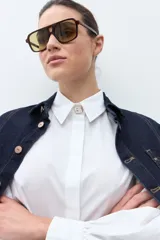 Camisa blanca de manga larga con puños fruncidos y cuello abotonado, corte holgado.