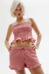 Short de algodón con estampado de cuadros vichy rojos y blancos, cintura elástica con moña de satén y ribete de volados en el bajo.