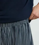 Conjunto de pijama corto para hombre, compuesto por una remera de manga corta con cuello redondo y bolsillo en el pecho, y un short con cintura elástica. Diseño a rayas finas.