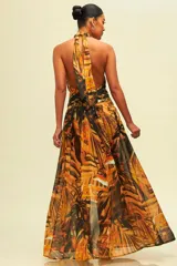 Vestido largo con estampado de hojas en tonos naranja y negro, con cuello halter y abertura en la pierna.