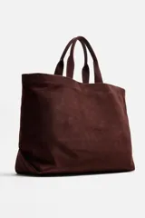 Bolso tipo shopper marrón de piel con acabado serraje. Tiene dos asas de mano y un bolsillo interior con cierre.