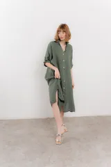 Vestido camisero midi color verde militar, de lino 100%, con silueta oversize, cuello camisero, mangas 3/4 con botón para ajustar y aberturas laterales.
