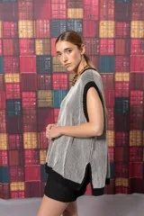 Chaleco largo de punto con rayas verticales en tonos beige y negro. Tiene cuello redondo, sisas amplias con ribete negro y aberturas laterales en el ruedo.