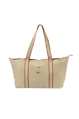 Bolso tipo tote color beige con asas de hombro de cinta con borde marrón. Tiene un bolsillo externo con botón a presión y un pequeño bordado con logo.